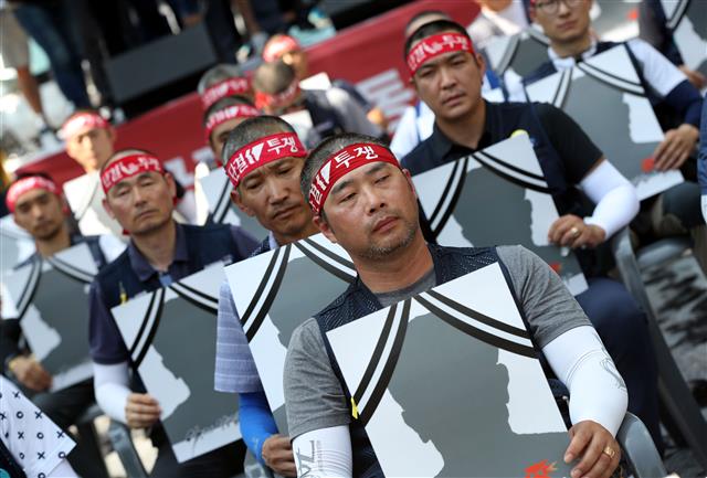 전국집배노동조합원들이 6일 오후 청와대 사랑채 앞에서 열린 우정노동자 총파업 결의대회에서 토요택배 폐지와 정규인력 증원 등을 촉구하며 삭발식을 마친뒤 영정사진 손피켓을 들고 있다.2019.7.6 뉴스1