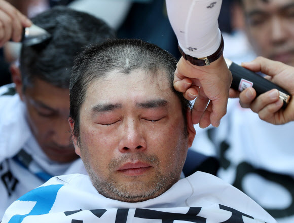 6일 서울 종로구 청와대 사랑채 인근에서 ‘토요택배 완전 폐지 및 정규인력 증원’ 등을 촉구하며 열린 우정노동자 총파업 결의대회에서 한 조합원이 눈물을 흘리며 삭발을 하고 있다. 2019.7.6  연합뉴스