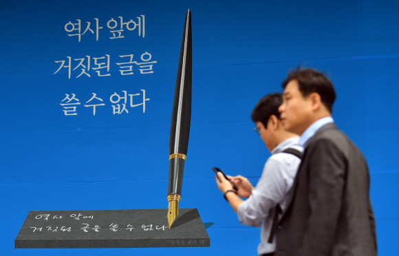16일 서울 프레스센터에서 열린 ‘굽히지 않는 펜’ 제막식 현수막 앞을 시민이 지나가고 있다. 2019. 07.16. 박지환 기자 popocar@seoul.co.kr