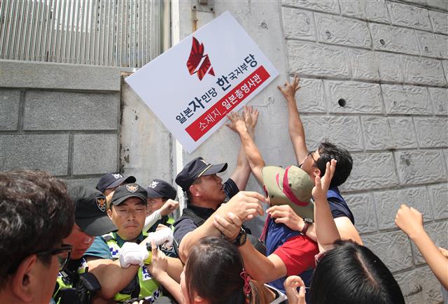 17일 오후 부산 동구 초량동 일본영사관 앞에서 적폐청산·사회대개혁 부산운동본부원들이 자유한국당을 규탄하는 기자회견 중 일본영사관 벽에 현판 부착 퍼포먼스를 선보이고 있다. 앞서 나경원 자유한국당 원내대표는 “문재인 대통령이 지금과 같이 직접 대일 강경대응에 나서는 것은 바람직하지 않다.”고 말했다. 2019.7.17 뉴스1