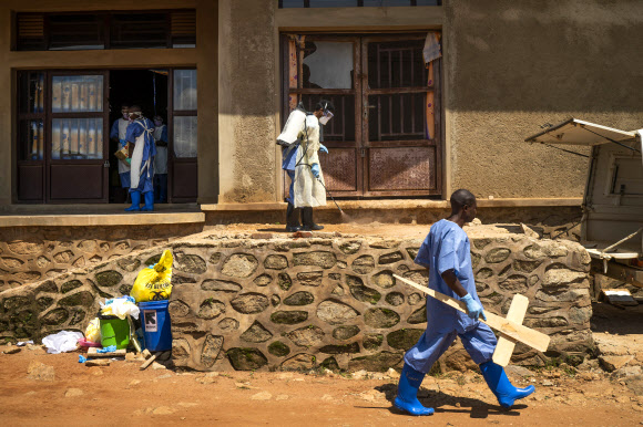 에볼라 바이러스가 창궐하는 콩고 베니에서 한 영안실 직원이 십자가를 들고 한 골목길을 지나가고 있다. 사진은 지난 14일(현시간) 촬영된 것이다. 베니(콩고) AP 연합뉴스