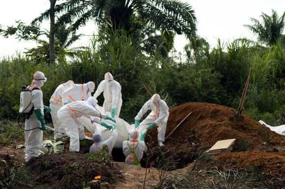 콩고 베니에서 위생복 차림의 사람들이 지난 14일(현지시간) 에볼라 바이러스로 숨진 주민의 시신을 무슬림 공동묘지에 묘장하고 있다. 베니(콩고) AP 연합뉴스