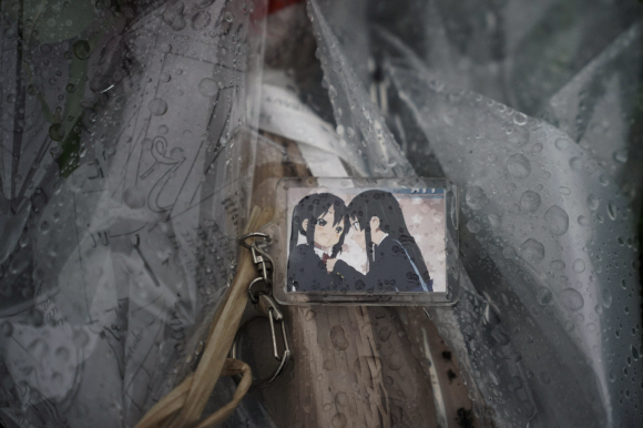 A keychain with a cartoon image is placed on top of flowers placed near the Kyoto Animation Studio building destroyed in an attack Friday, July 19, 2019, in Kyoto, Japan. A man screaming “You die!” burst into the animation studio in Kyoto, doused it with a flammable liquid and set it on fire Thursday, killing dozens of people in the attack that shocked the country and brought an outpouring of grief from anime fans. (AP Photo/Jae C. Hong)/2019-07-19 08:45:12/ <저작권자 ⓒ 1980-2019 ㈜연합뉴스. 무단 전재 재배포 금지.>