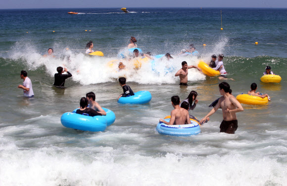 중복인 22일 강원 강릉시 경포해수욕장을 찾은 피서객들이 파도를 타며 무더위를 식히고 있다. 강릉의 기온은 이날 오후 3시 33.9도까지 올랐다. 2019.7.22  연합뉴스