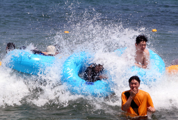 중복인 22일 강원 강릉시 경포해수욕장을 찾은 피서객들이 파도를 타며 무더위를 식히고 있다. 강릉의 기온은 이날 오후 3시 33.9도까지 올랐다. 2019.7.22  연합뉴스