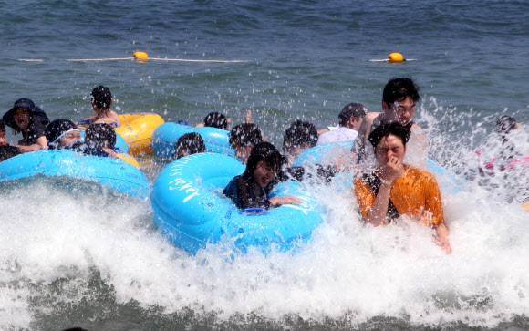 중복인 22일 강원 강릉시 경포해수욕장을 찾은 피서객들이 파도를 타며 무더위를 식히고 있다. 강릉의 기온은 이날 오후 3시 33.9도까지 올랐다. 2019.7.22  연합뉴스