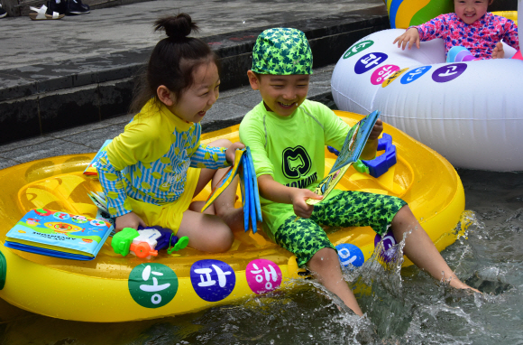 대서인 23일 서울 송파구 성내천을 찾은 어린이들이 물놀이와 독서를 동시에 즐기고 있다. 송파구는 성내천 물놀이장에 도서를 비치하고 파라솔과 테이블 등 독서 공간을 제공하는 ‘여름행복문고’를 일주일간 운영한다고 밝혔다.  2019.7.23.   이종원 선임기자 jongwon@seoul.co.kr