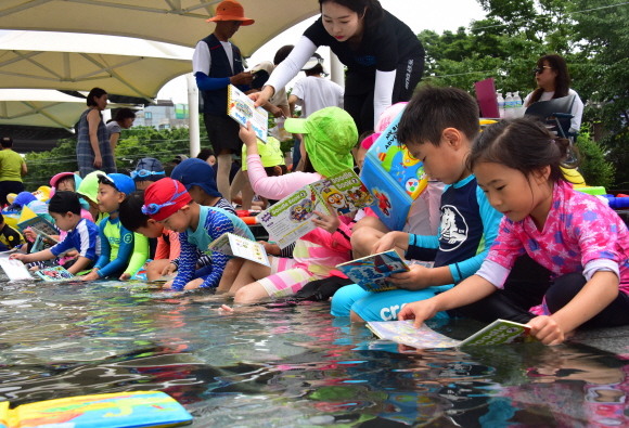 대서인 23일 서울 송파구 성내천을 찾은 어린이들이 물놀이와 독서를 동시에 즐기고 있다. 송파구는 성내천 물놀이장에 도서를 비치하고 파라솔과 테이블 등 독서 공간을 제공하는 ‘여름행복문고’를 일주일간 운영한다고 밝혔다.  2019.7.23.   이종원 선임기자 jongwon@seoul.co.kr