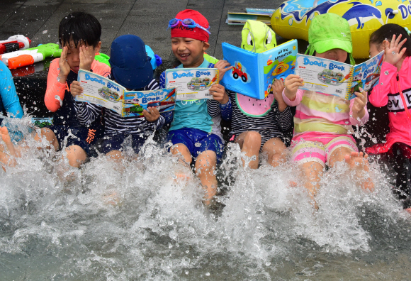 대서인 23일 서울 송파구 성내천을 찾은 어린이들이 물놀이와 독서를 동시에 즐기고 있다. 송파구는 성내천 물놀이장에 도서를 비치하고 파라솔과 테이블 등 독서 공간을 제공하는 ‘여름행복문고’를 일주일간 운영한다고 밝혔다.  2019.7.23.   이종원 선임기자 jongwon@seoul.co.kr