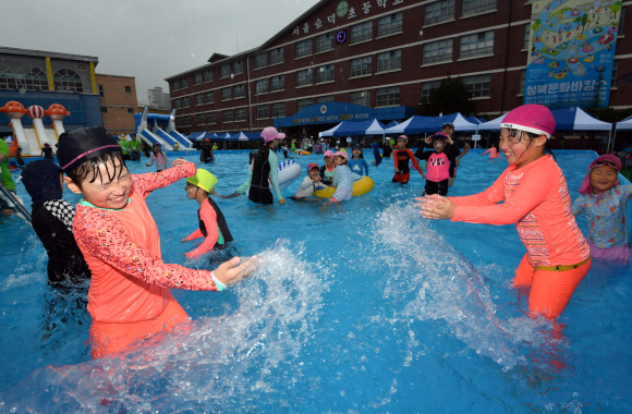 28일 서울 숭덕초등학교 에서 열린 성북문화바캉스에서 어린이들이 학교 운동장에 마련된 수영장에서 즐거운 표정으로 물놀이를 즐기고 있다. 2019.7.28 박지환기자 popocar@seoul.co.kr