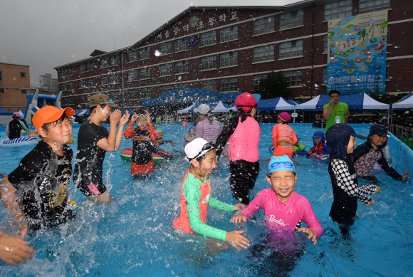 28일 서울 숭덕초등학교 에서 열린 성북문화바캉스에서 어린이들이 학교 운동장에 마련된 수영장에서 즐거운 표정으로 물놀이를 즐기고 있다. 2019.7.28 박지환기자 popocar@seoul.co.kr