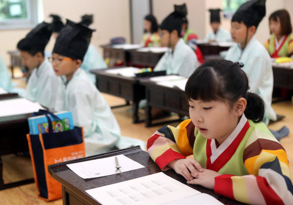 29일 부산 동래구 충렬사 안락서원 교육회관에서 열린 전통서당 체험 교실에서 학생들이 한복을 입고 사자소학을 배우고 있다. 충렬사 안락서원 교육회관은 여름방학을 맞아 초등학생 50명을 상대로 전통예절·다도·서당체험과 전통 민속놀이(떡메치기, 투호, 제기차기) 프로그램을 운영한다. 2019.7.29  연합뉴스