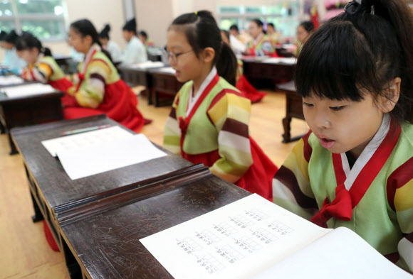 29일 부산 동래구 충렬사 안락서원 교육회관에서 열린 전통서당 체험 교실에서 학생들이 한복을 입고 사자소학을 배우고 있다. 충렬사 안락서원 교육회관은 여름방학을 맞아 초등학생 50명을 상대로 전통예절·다도·서당체험과 전통 민속놀이(떡메치기, 투호, 제기차기) 프로그램을 운영한다. 2019.7.29  연합뉴스