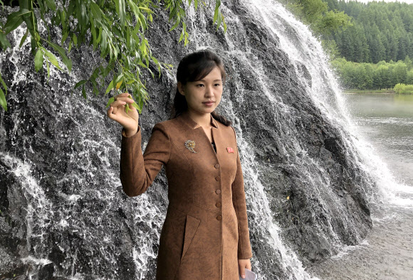 북한 여성이 지난 24일 백두산 폭포에서 사진을 찍기 위해 포즈를 취하고 있다. TASS=연합뉴스