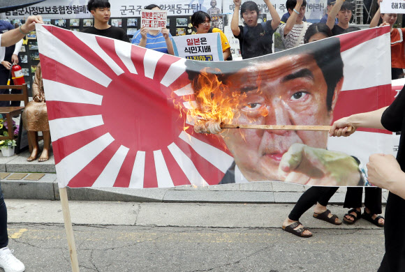 한국대학생진보연합 학생들이 29일 오후 서울 종로구 옛 주한일본대사관 앞 소녀상에서 일본의 강제징용 사죄 촉구 및 전범 기업 규탄 기자회견을 하던 중 욱일기와 아베 총리 사진을 불태우고 있다. 2019.7.29  연합뉴스