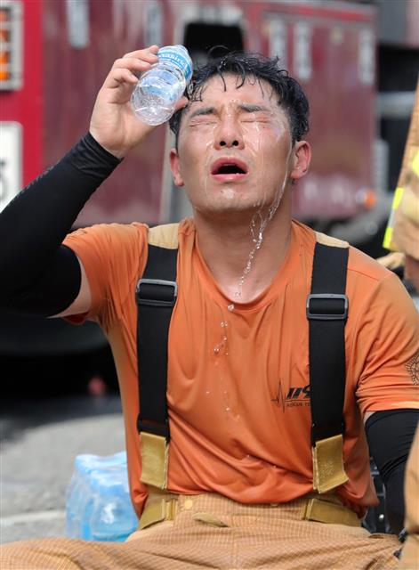 전국 대부분 지역예 폭염특보가 발효된 29일 오후 전북 전주시 송천동 상가건물에서 불이나 출동한 소방관이 화재 진압을 마친 뒤 얼굴에 물을 뿌리며 더위를 식히고 있다.2019.7.29 뉴스1