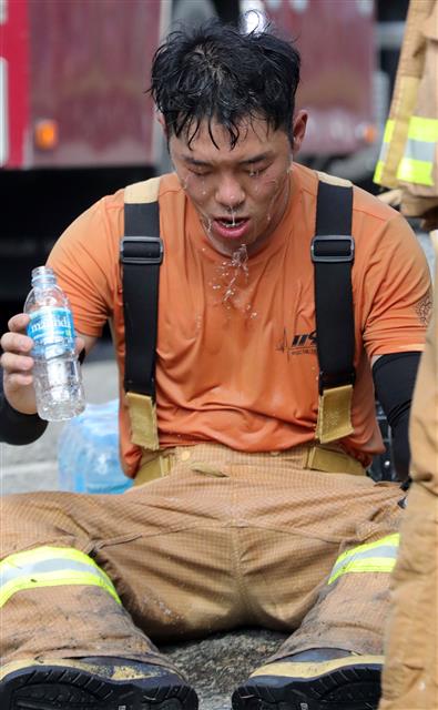 전국 대부분 지역예 폭염특보가 발효된 29일 오후 전북 전주시 송천동 상가건물에서 불이나 출동한 소방관이 화재 진압을 마친 뒤 얼굴에 물을 뿌리며 더위를 식히고 있다.2019.7.29 뉴스1