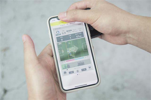 FC 원터치의 한 선수가 경기가 끝난 뒤 스마트폰 화면에 나타난 자신의 공격 방향, 평점 등 경기 데이터를 확인하고 팀원들에게 보여 주고 있다.