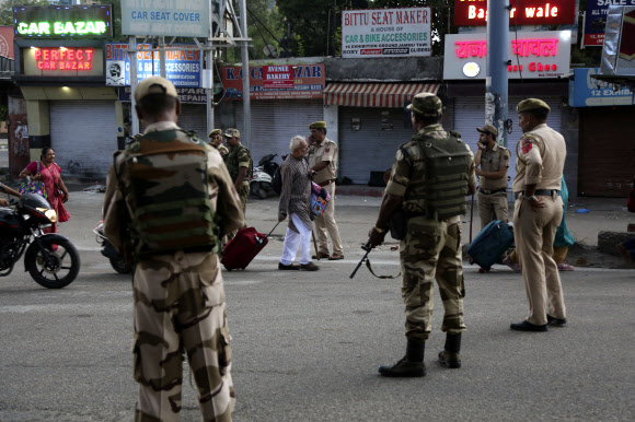 5일 인도령 잠무지역에서 무장한 인도 군인이 길거리에서 지나가는 주민들을 지켜보고 있다. 인도 연방정부가 카슈미르에 대한 특별 지위를 페지한다고 발표하면서 인도 군인들이 이 지역에서 삼엄한 경계를 펴고 있다. AP 연합뉴스