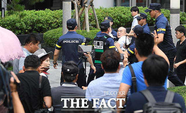 8일 서울 종로구 옛 일본대사관 앞에서 열린 엄마부대봉사단의 기자회견에 앞서 한 남성이 주옥순 엄마부대 대표를 향해 밀가루 봉지를 던지고 있다. 경찰이 두 사람를 떨어뜨려 놓으면서 주옥순 대표는 밀가루에 맞지는 않았다. 2019.8.8  더팩트