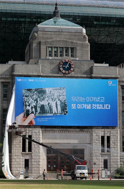 11일 서울 중구 서울도서관 외벽에서 관계자들이 서울광장 꿈새김판을 교체하고 있다. 서울시는 광복 제74주년을 맞아 ‘우리는 이겨냈고 또 이겨낼 것입니다’라는 문구로 꿈새김판을 교체했다. 서울시는 최근 불거지고 있는 한·일간 경제·외교적 분쟁 등 광복 이후에도 남아있는 갈등을 전 시민들과 지혜롭게 극복하자는 염원을 담아 이번 꿈새김판을 기획했다고 밝혔다. 2019.8.11 뉴스1
