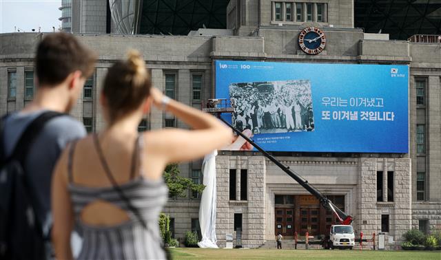 11일 서울 중구 서울도서관 외벽에서 관계자들이 서울광장 꿈새김판을 교체하고 있다. 서울시는 광복 제74주년을 맞아 ‘우리는 이겨냈고 또 이겨낼 것입니다’라는 문구로 꿈새김판을 교체했다. 서울시는 최근 불거지고 있는 한·일간 경제·외교적 분쟁 등 광복 이후에도 남아있는 갈등을 전 시민들과 지혜롭게 극복하자는 염원을 담아 이번 꿈새김판을 기획했다고 밝혔다. 2019.8.11 뉴스1