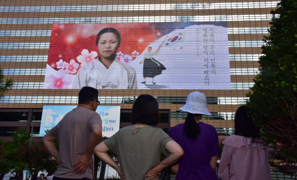 광복절을 앞둔 11일, 서울 종로구 교보생명빌딩 외벽에서 유관순 열사의 모습을 담은 초대형 래핑(Wrapping)작업을 하고 있다. 이번 래핑은 대한민국 임시정부 수립 100주년을 맞아 독립의 의미를 되새기고 독립열사의 숭고한 희생을 기리기 위해 제작됐다. 2019.8.11.    이종원 선임기자 jongwon@seoul.co.kr