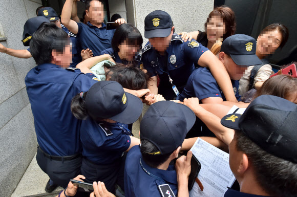 전남편 살해 혐의로 구속기소된 고유정이 12일 제주지법에서 첫 재판을 받고 나와 호송차에 오르기 전 한 시민에게 머리채를 잡히고 있다. 제주 연합뉴스