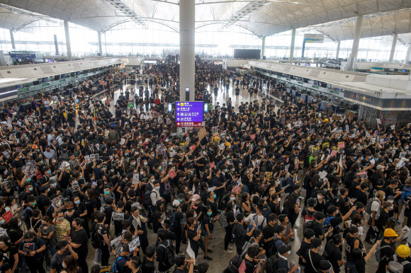 ‘범죄인 인도 법안’(송환법)에 반대하는 홍콩 시위대가 12일 홍콩 국제공항 출국장에 모여 시위를 벌이고 있다. 이날 수천 명의 시위대가 홍콩 국제공항에 몰려 연좌시위를 벌이면서 여객기 운항이 전면 중단됐다. 로이터 연합뉴스