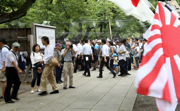 일본의 패전일이자 한국의 광복절인 15일 일본 도쿄(東京) 야스쿠니신사(靖國神社)에서 전범기인 욱일기(旭日旗)가 휘날리는 가운데 참배객들이 걸어가고 있다. 2019.8.15  연합뉴스