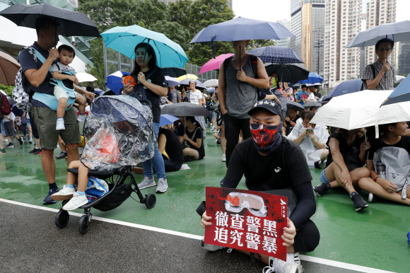 홍콩과 러시아에서 20대의 주도하에 정치적 개혁과 변화를 요구하는 반정부 시위가 이어지고 있다. 사진은 ‘범죄인인도법안’(송환법)에 반대하며 11주째 대규모 주말 시위가 열린 빅토리아 공원에서 지난 18일 어린 자녀를 데리고 나온 홍콩 시민들이 우산을 받쳐 들고 비를 피하고 있다. 홍콩 AP 연합뉴스