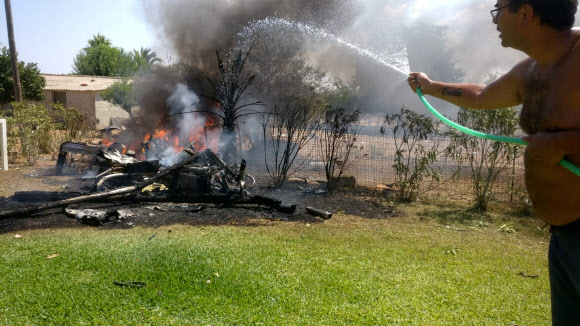 스페인 마요르카섬의 한 주민이 25일(현지시간) 헬리콥터와 경비행기의 공중 충돌로 적어도 7명이 숨진 가운데 지상에 떨어진 잔해에다 물을 뿌려 불을 끄려 하고 있다. 인카 로이터 연합뉴스 