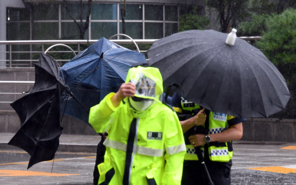 폭우가 내린 29일 서울 종로구 적선현대빌딩에 인근에서 경찰들이 우산으로 간신히 비를 막고 있다.2019. 8. 29. 박윤슬 기자 seul@seoul.co.kr