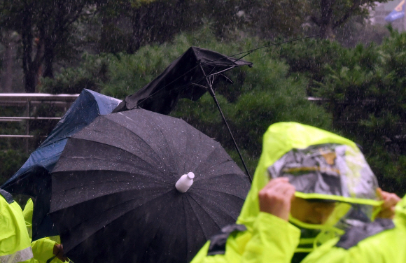 폭우가 내린 29일 서울 종로구 적선현대빌딩에 인근에서 경찰들이 우산으로 간신히 비를 막고 있다.2019. 8. 29. 박윤슬 기자 seul@seoul.co.kr