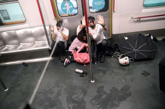 홍콩에서 범죄인 송환법안에 반대하는 시위가 13주 연속으로 열린 지난달 31일(현지시간) 프린스 에드워드역에 멈춰 선 열차 안에서 시위대원들이 주저앉은 채 경찰이 뿌린 최루액을 맞고 있다. 홍콩 AP 연합뉴스