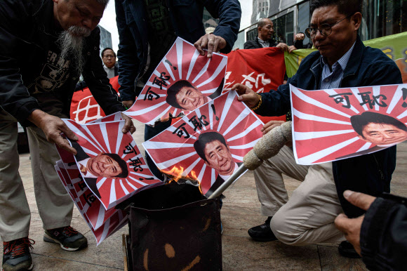 2017년 12월 13일 난징대학살 추모행사에서 중국 시민들이 아베 신조 총리의 얼굴이 들어간 욱일기 문양을 불태우고 있다.  AFP 연합뉴스