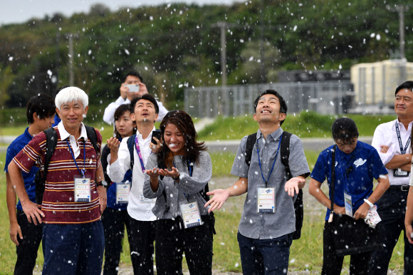 도쿄 하계올림픽 조직위원회 직원들이 13일 인공 눈 실험으로 내리는 눈을 맞으며 즐거워하고 있다. 도쿄 AFP 연합뉴스 