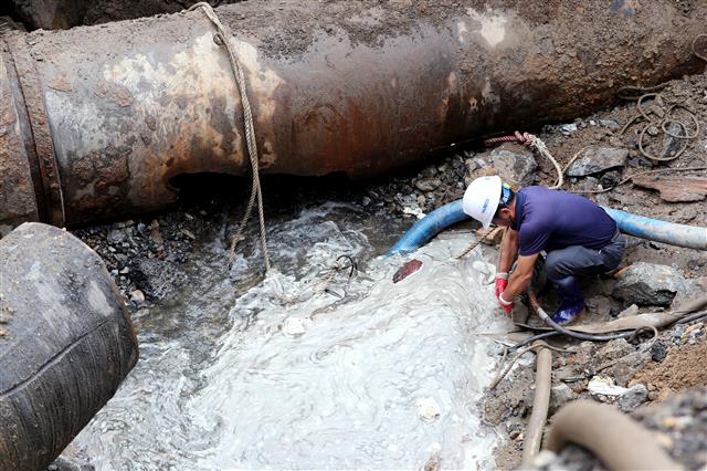 14일 오전 경기 안양시 동안구 인덕원역 사거리 광역 상수관 파열 현장에서 관계자들이 긴급 복구 작업을 벌이고 있다.  전날 밤 발생한 이 사고로 이지역 일대 지반이 일부 내려앉아 차량 10여대가 침수되고 현재 인덕원역 앞 편도 7차로 도로 300여m 구간 일부가 통제되고 있다. 2019.9.14 뉴스1