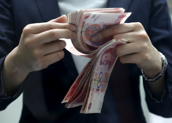 중국의 시중 은행들이 16일 지급준비율(지준율)을 0.5%포인트 인하했다. 사진은 지난 2016년 1월 4일 베이징의 한 은행 지점에서 은행원이 100위안짜리 인민폐를 세고 있는 모습. 베이징 로이터 연합뉴스