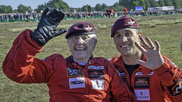 75년 만에 네덜란드 아른헴 침투 낙하작전 재현 행사에 참가한 영국의 97세 노병 샌디 코트먼(왼쪽)이 낙하산을 함께 펼쳐준 병사와 함께 손을 들어 보이고 있다. PA 미디어 BBC 홈페이지 캡처