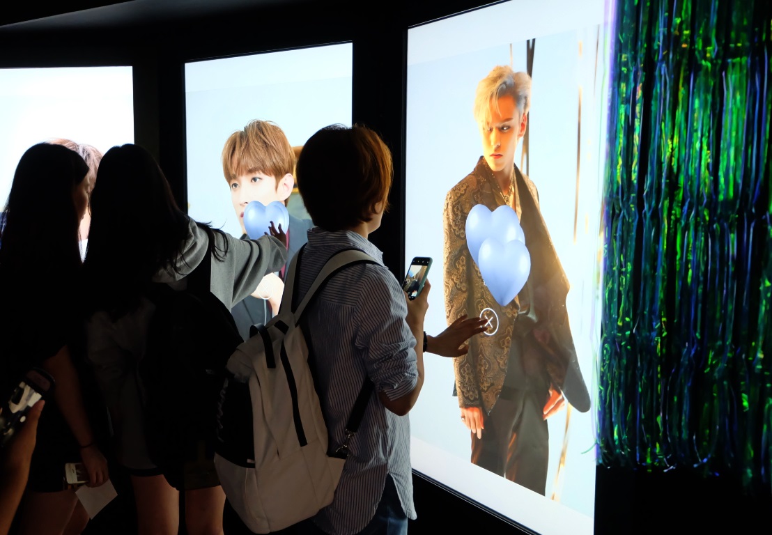 서울 중구 롯데백화점 영플라자 명동점 지하 1층에서 오는 30일까지 운영되는 세븐틴의 ‘콘셉트 존’에서 팬들이 미공개 사진들을 보며 하트를 누르고 있다.