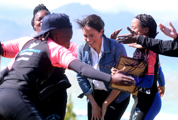 영국 메간 마클(가운데) 왕자비가 24일(현지시간) 남아프리카 케이프타운의 몬와비시 해변에서 NGO ‘Waves for Change’을 방문하는 동안 그룹 활동으로 서핑 강사 멘토들과 함께하고 있다. EPA 연합뉴스