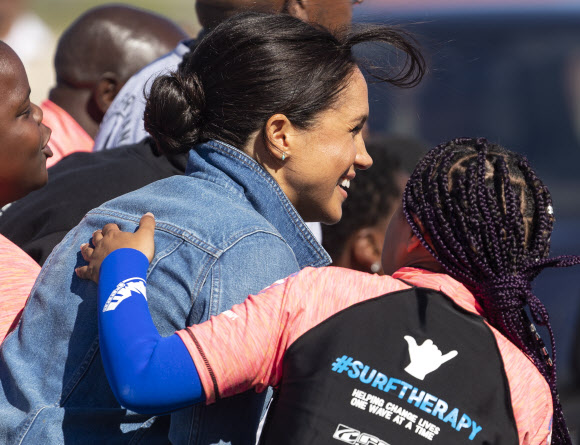 영국 메간 마클(가운데) 왕자비가 24일(현지시간) 남아프리카 케이프타운의 몬와비시 해변에서 NGO ‘Waves for Change’을 방문하는 동안 그룹 활동으로 서핑 강사 멘토들과 함께하고 있다. EPA 연합뉴스