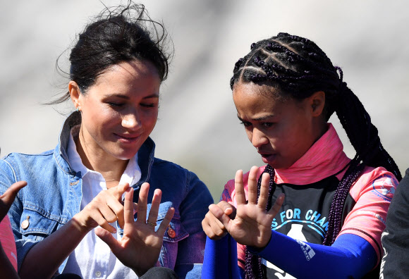 영국 메간 마클(왼쪽) 왕자비가 24일(현지시간) 남아프리카 케이프타운의 몬와비시 해변에서 NGO ‘Waves for Change’을 방문하는 동안 그룹 활동으로 서핑 강사 멘토들과 함께하고 있다. EPA 연합뉴스