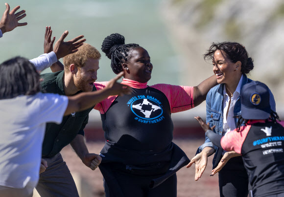 영국 해리(왼쪽 두 번째) 왕자와 메간 마클(오른쪽) 왕자비가 24일(현지시간) 남아프리카 케이프타운의 몬와비시 해변에서 NGO ‘Waves for Change’을 방문하는 동안 그룹 활동으로 서핑 강사 멘토들과 함께하고 있다. EPA 연합뉴스