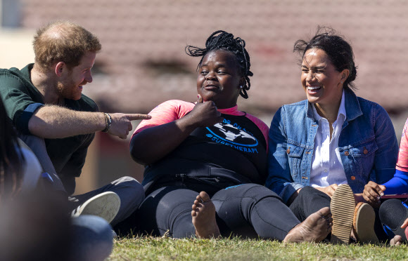 영국 해리(왼쪽) 왕자와 메간 마클(오른쪽) 왕자비가 24일(현지시간) 남아프리카 케이프타운의 몬와비시 해변에서 NGO ‘Waves for Change’을 방문하는 동안 그룹 활동으로 서핑 강사 멘토들과 함께하고 있다. EPA 연합뉴스