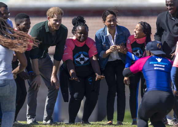 영국 해리(왼쪽 세 번째) 왕자와 메간 마클(다섯 번째) 왕자비가 24일(현지시간) 남아프리카 케이프타운의 몬와비시 해변에서 NGO ‘Waves for Change’을 방문하는 동안 그룹 활동으로 서핑 강사 멘토들과 함께하고 있다. EPA 연합뉴스