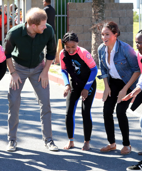 영국 해리(왼쪽) 왕자와 메간 마클(오른쪽) 왕자비가 24일(현지시간) 남아프리카 케이프타운의 몬와비시 해변에서 NGO ‘Waves for Change’을 방문하는 동안 그룹 활동으로 서핑 강사 멘토들과 함께하고 있다. EPA 연합뉴스