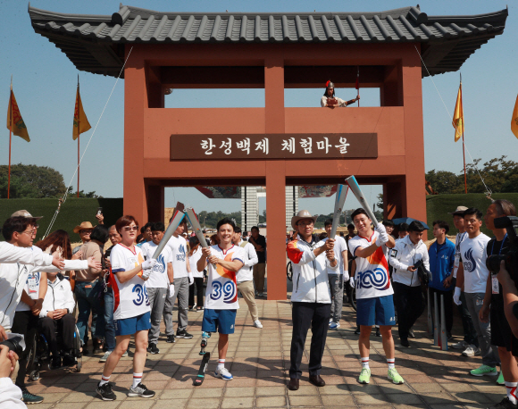 ‘전국체전 성공을 기원하며’ 토치키스  29일 오후 서울 송파구 올림픽공원 평화의 광장 앞에서 열린 제100회 전국체전 및 제39회 전국장애인체전 성화 봉송 행사에서 성화 주자들이 토치 키스를 하고 있다. 왼쪽부터 아시안게임 육상 3관왕 임춘애, 한국 장애인 아이스하키 대표팀 정승환, 서울시 관광체육국 주용태 국장, 올림픽 사격 금메달리스트 진종오. 2019. 09.29. 정연호 기자 tpgod@seoul.co.kr