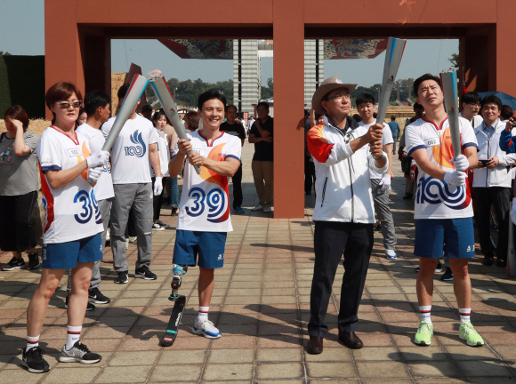 ‘전국체전 성공을 기원하며’ 토치키스  29일 오후 서울 송파구 올림픽공원 평화의 광장 앞에서 열린 제100회 전국체전 및 제39회 전국장애인체전 성화 봉송 행사에서 성화 주자들이 토치 키스를 하고 있다. 왼쪽부터 아시안게임 육상 3관왕 임춘애, 한국 장애인 아이스하키 대표팀 정승환, 서울시 관광체육국 주용태 국장, 올림픽 사격 금메달리스트 진종오. 2019. 09.29. 정연호 기자 tpgod@seoul.co.kr